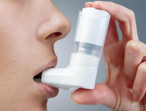 Close up of a person using an inhaler.