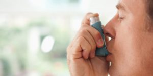 Close up of a middled age man using inhaler.