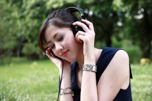 Asian woman enjoying the outdoors with headphones on.
