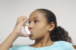Black young girl using an inhaler.