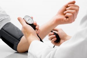 Doctor checking patient's blood pressure manually.