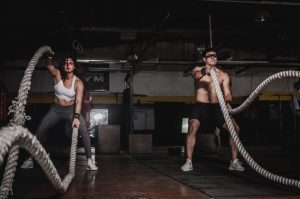 Man and woman doing crossfit battle ropes.