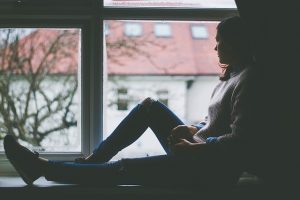 Woman sitting by window as she looks outside.