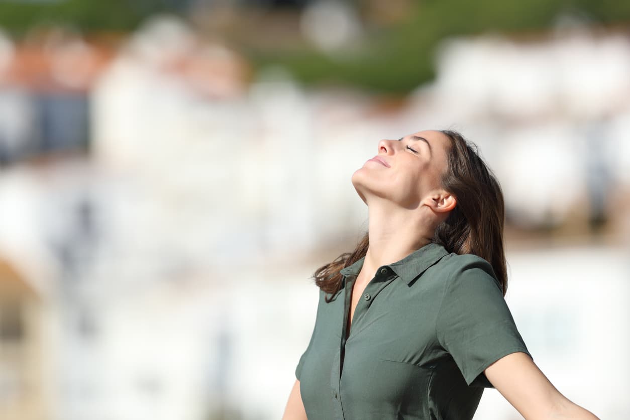 A woman smiling and taking a deep breath to reduce stress