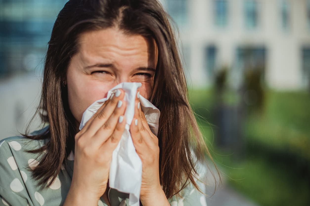 A woman sneezing and holding a tissue to her nose